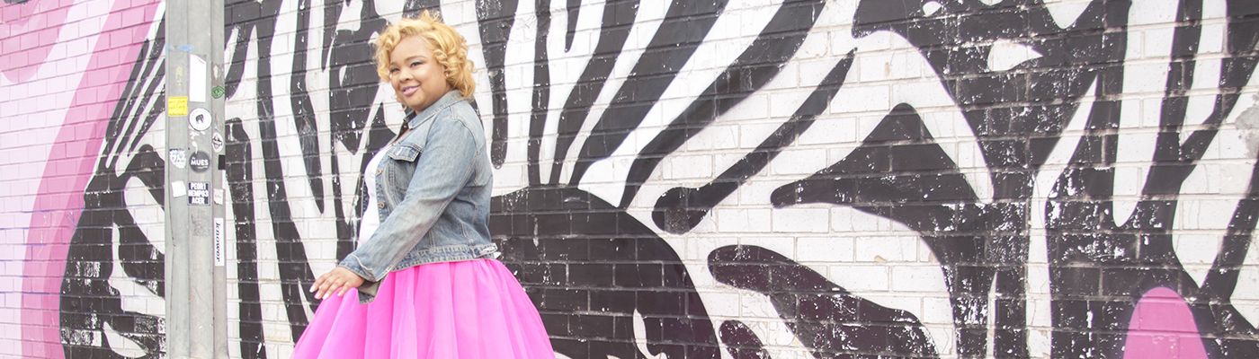 Diana Veiga standing in front of a black, white, and pink mural
